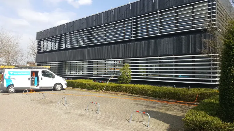 Bedrijfswagen van Diamond Cleaning Belgium voor een kantoorgebouw met aluminium gevellamellen