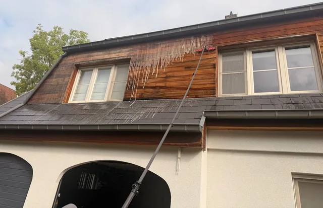 Houten gevelbekleding wordt met een telescoopborstel gereinigd