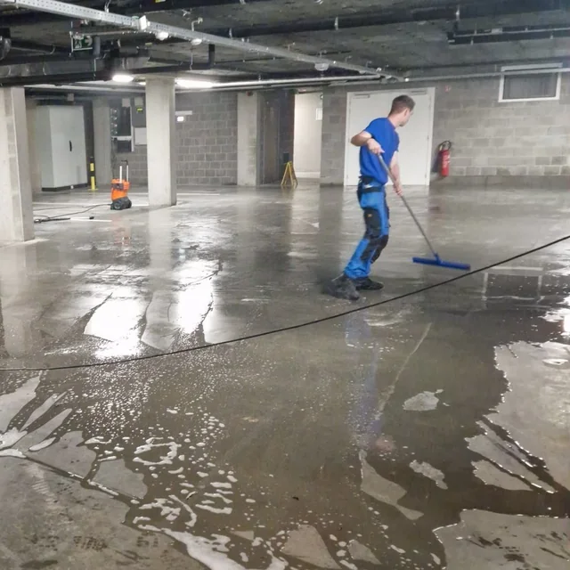 Medewerker trekt water en vuil van een betonnen vloer