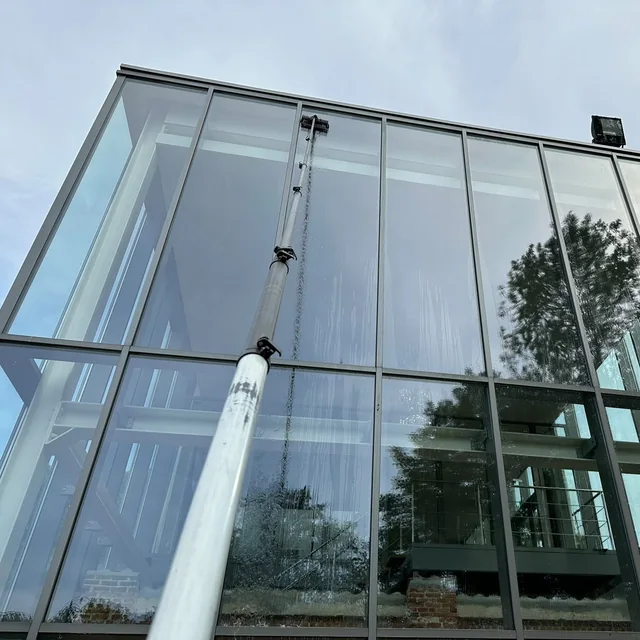 Borstel op een telescoopsteel wast een hoge glaspartij