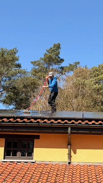 Medewerker reinigt zonnepanelen met een watergevoede borstel