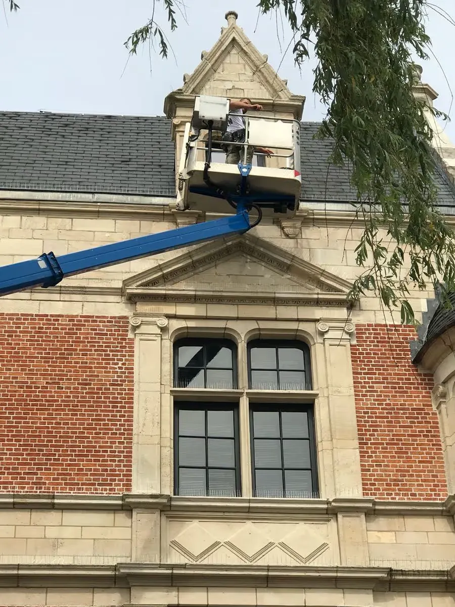 Hoogwerker aan de gevel van een historisch gebouw in Brasschaat tijdens het reinigen van de ramen