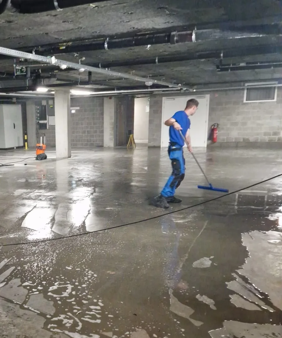 Medewerker reinigt een betonnen vloer in een parkeergarage
