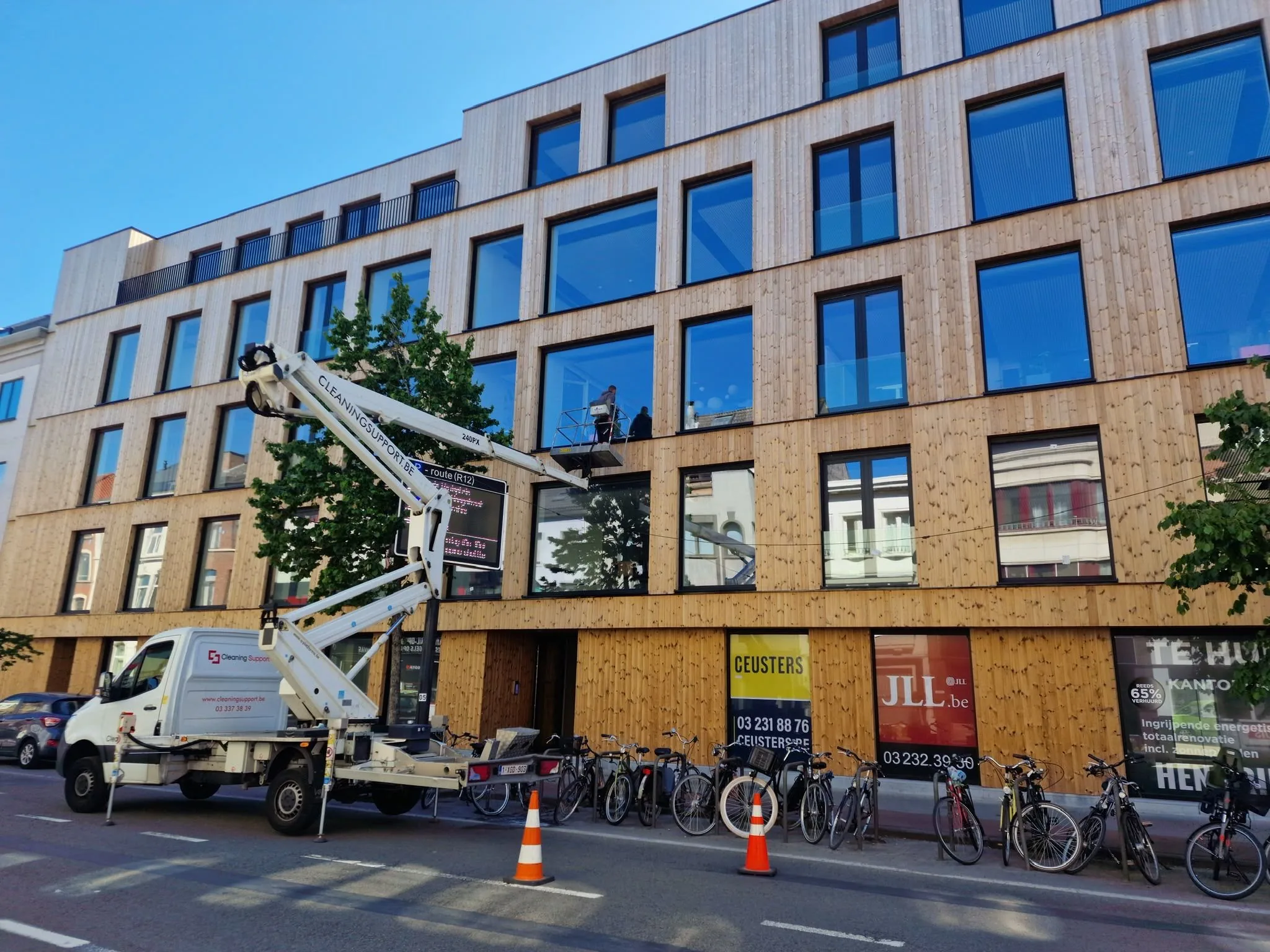 Hoogwerker aan een appartementsgebouw met houten gevel