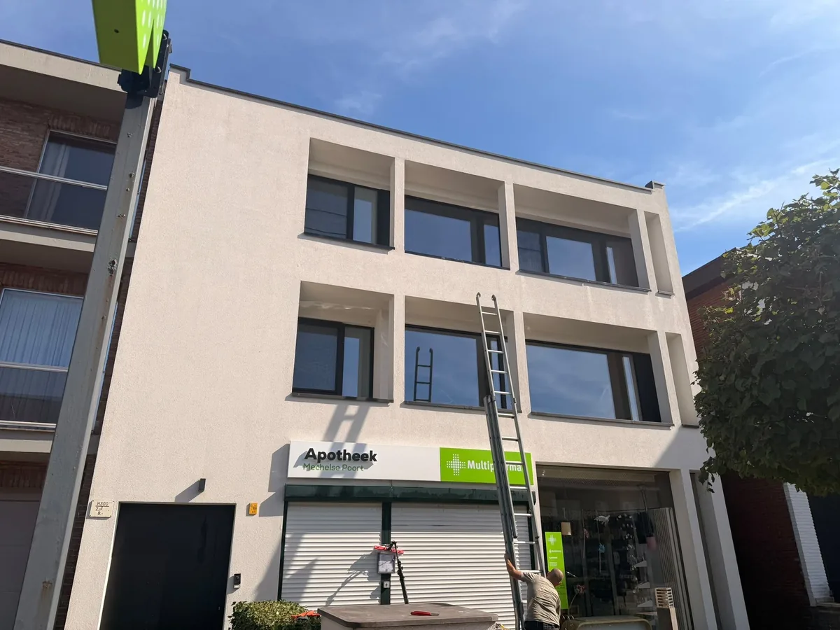 Ramenwas met ladder en telescoopsteel bij een winkelpand
