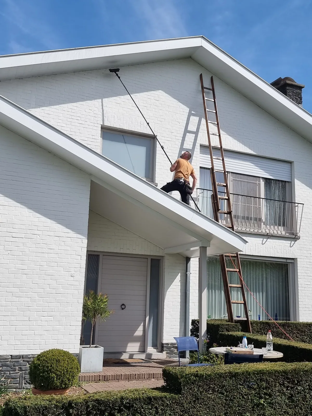 Ramenwasser reinigt de ramen van een woning met de telescoopsteel