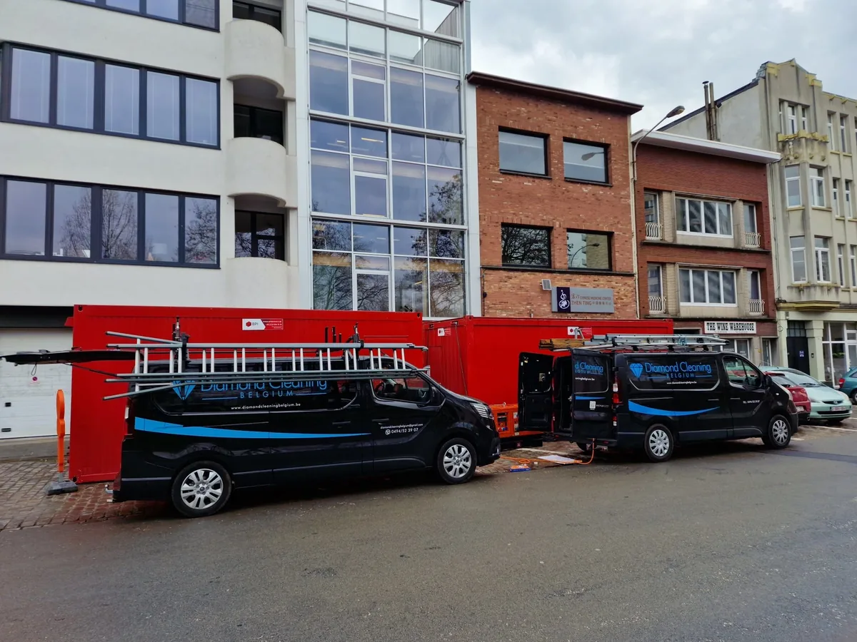 Twee zwarte bestelwagens van Diamond Cleaning in een straat, met de ladders op het dak