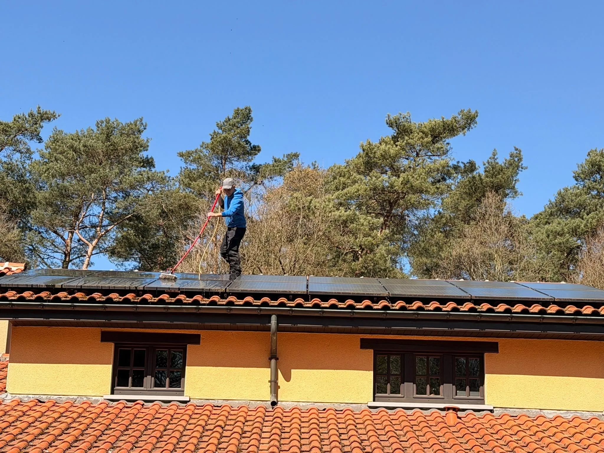 Medewerker reinigt zonnepanelen op het dak van een woning