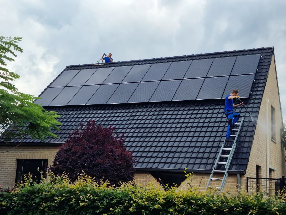Medewerker op de ladder bij zonnepanelen op een woning