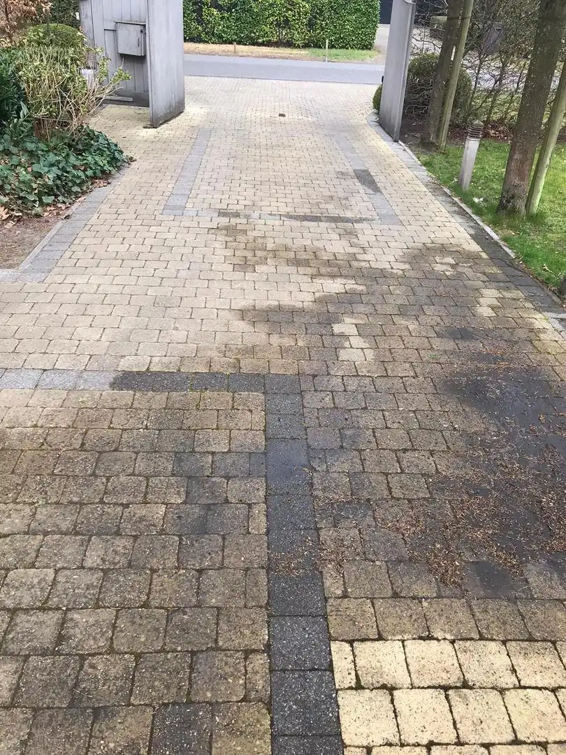 Oprit van klinkers, halfweg de reiniging: voor en na naast elkaar