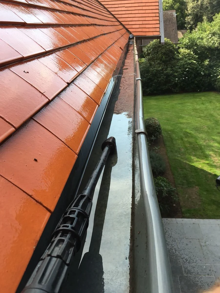 Dakgoot van een woning wordt leeggemaakt en doorgespoeld